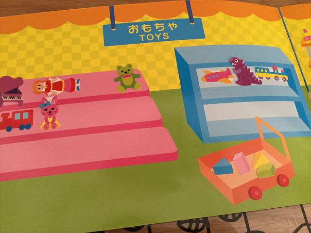 ダイソー「知育シールブック」おかいもの、おもちゃ売り場に人形やピアノなどのシールを貼った様子